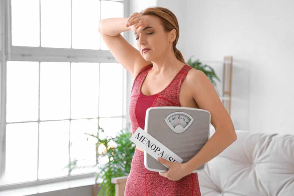 A woman experiencing hormone imbalances and weight gain holding a scale